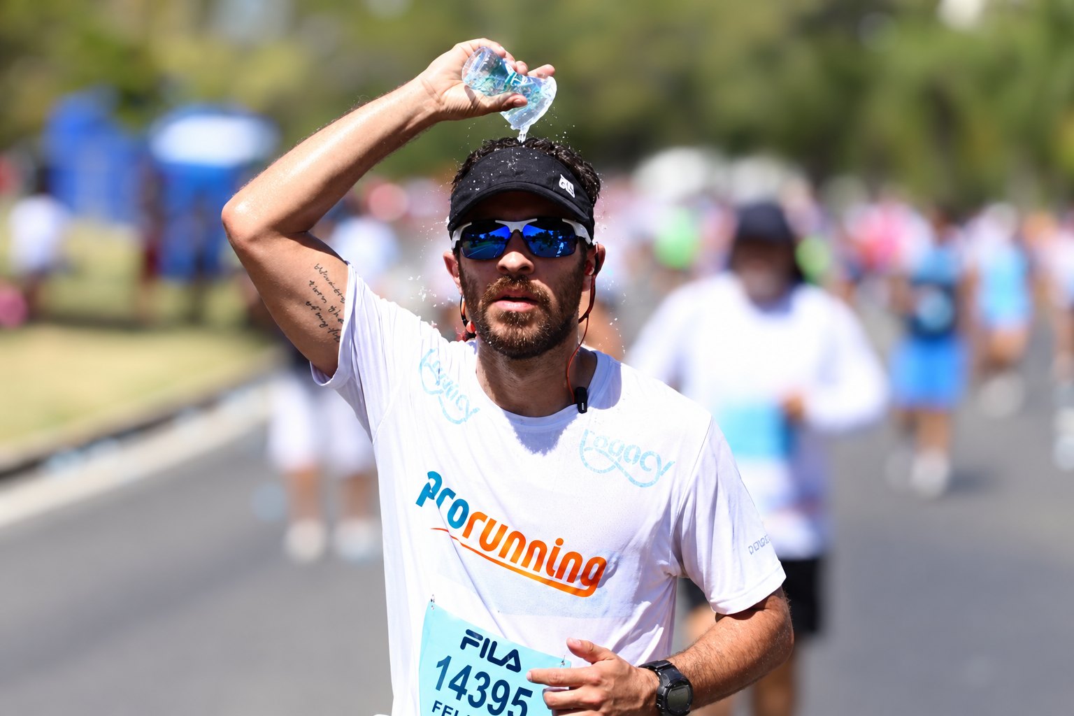 Corredor da ProRunning jogando água na cabeça para se refrescar durante uma prova de rua